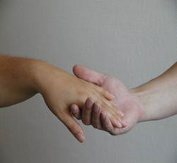 Das Bild zeigt zwei H�nde. Von rechts ragt eine M�nnerhand zur Mitte des Bildes. Sie ist nach oben ge�ffnet und h�lt  eine von links kommenden andere Hand. Die zweite Hand wird von der ersten gertragen. 