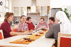Wir sind bei einer Dienstbesprechung zu Gast. Die Mitarbeiter sitzen zusammen und planen ihren Dienst. Eine MItarbeiterin dokumentiert das Gesagte.