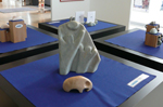 Wir befinden uns auf der Diele im Hospiz. Die Beteiligten haben sich vor den aufge-h�ngten Bildern aufgestellt.  Sie schauen uns freundlich an. Im Hintergrund sind an den hellen W�nden viele Bilder des K�nstlers aufgeh�ngt.